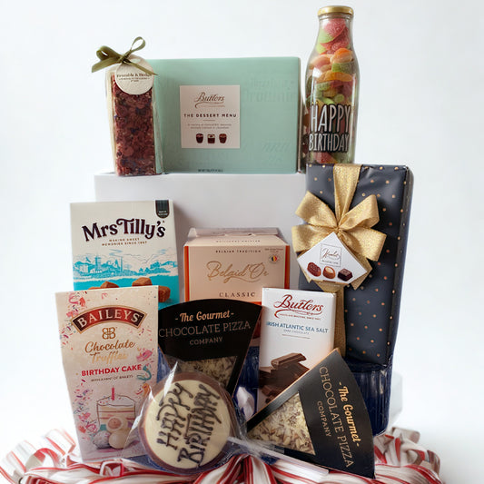 Gourmet gift basket with various items including a bottle, cookies, and a box on a white background